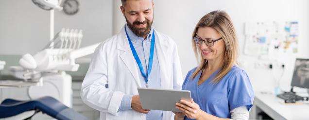 Dentista e secretária consultam tablet em clínica odontológica, em rotina de gestão com Simples Dental para organizar agenda, atendimento e fichas clínicas.